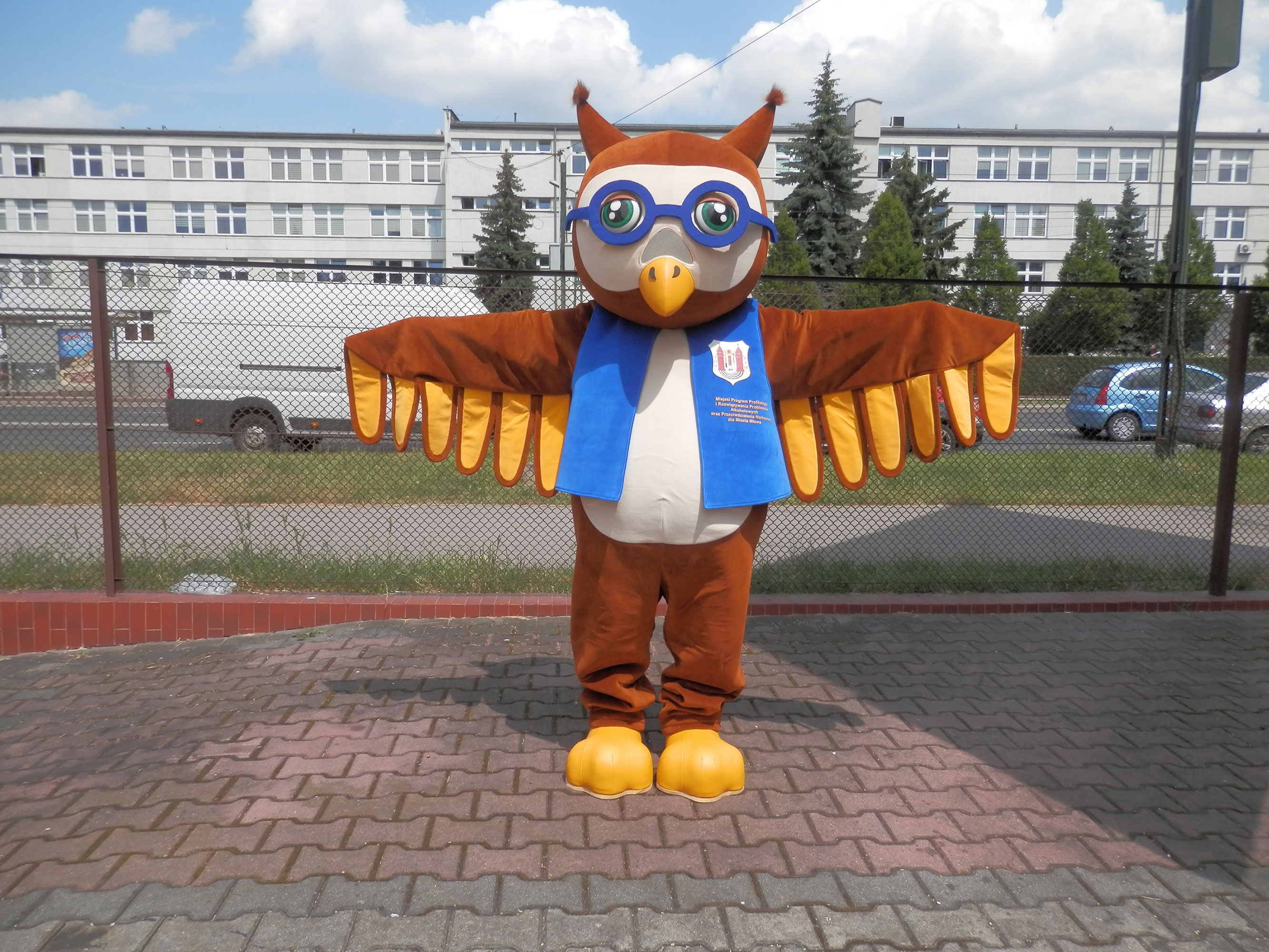 Na fotografii widnieje przebranie reklamowe w postaci sowy pozujące do zdjęcia w pobliżu siedziby firmy Elabika